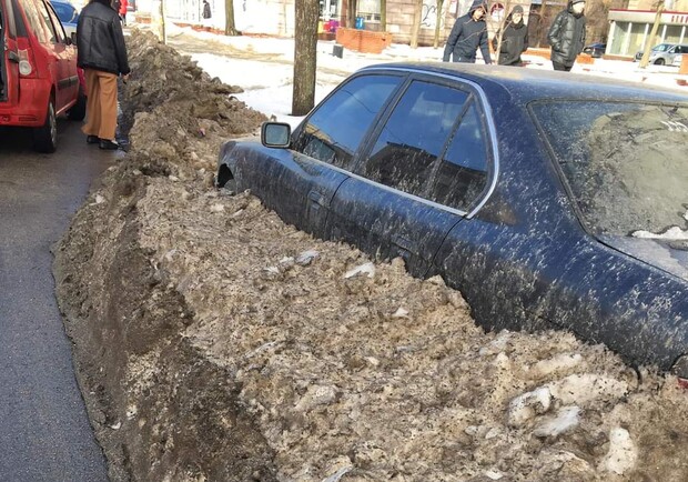 В Запорожье коммунальщики закопали машину в грязный снег 