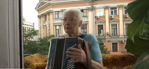 В центре Киева 76-летняя бабушка развлекает горожан игрой на баяне со своего балкона