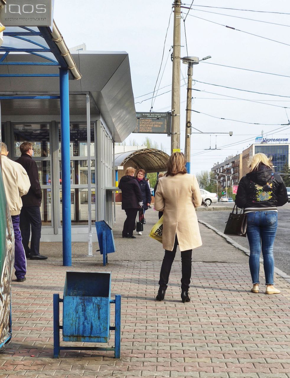 Женщина болтает на остановке, не надевая маску